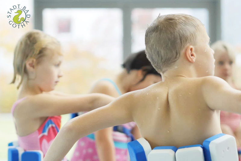 Sicht auf eine Gruppe Schüler mit Schwimmgürtel. Schwimmkurs für Kinder im Stadtbad Gotha.