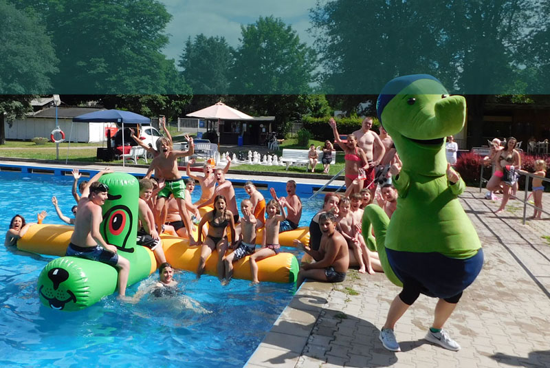 Sicht auf eine Gruppe fröhlicher Kinder im Freibad Stadtbad Gotha. Im Vordergrund unser Maskottchen Aqualino