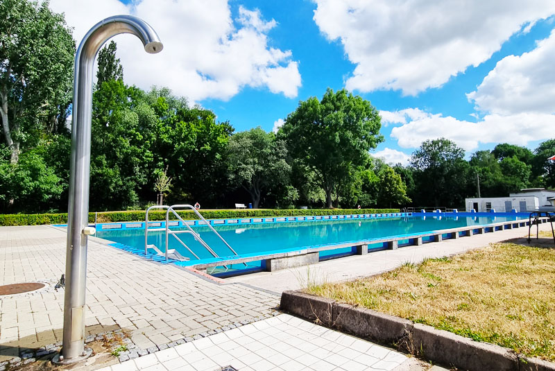 Sicht auf das Badebecken im Freibad des Stadtbades Gotha. Dusche im Vordergrund.