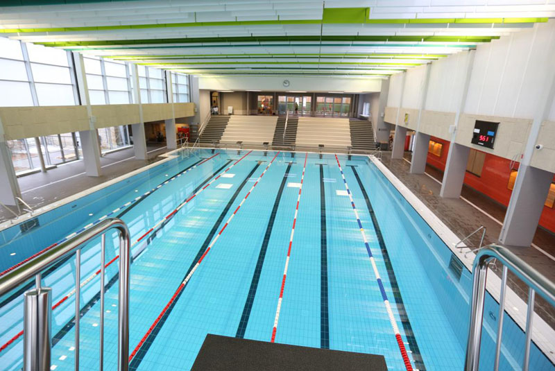Sicht auf das Schwimmbecken mit den gezogenen Bahnen vom 5-Meter-Sprungturm aus gesehen